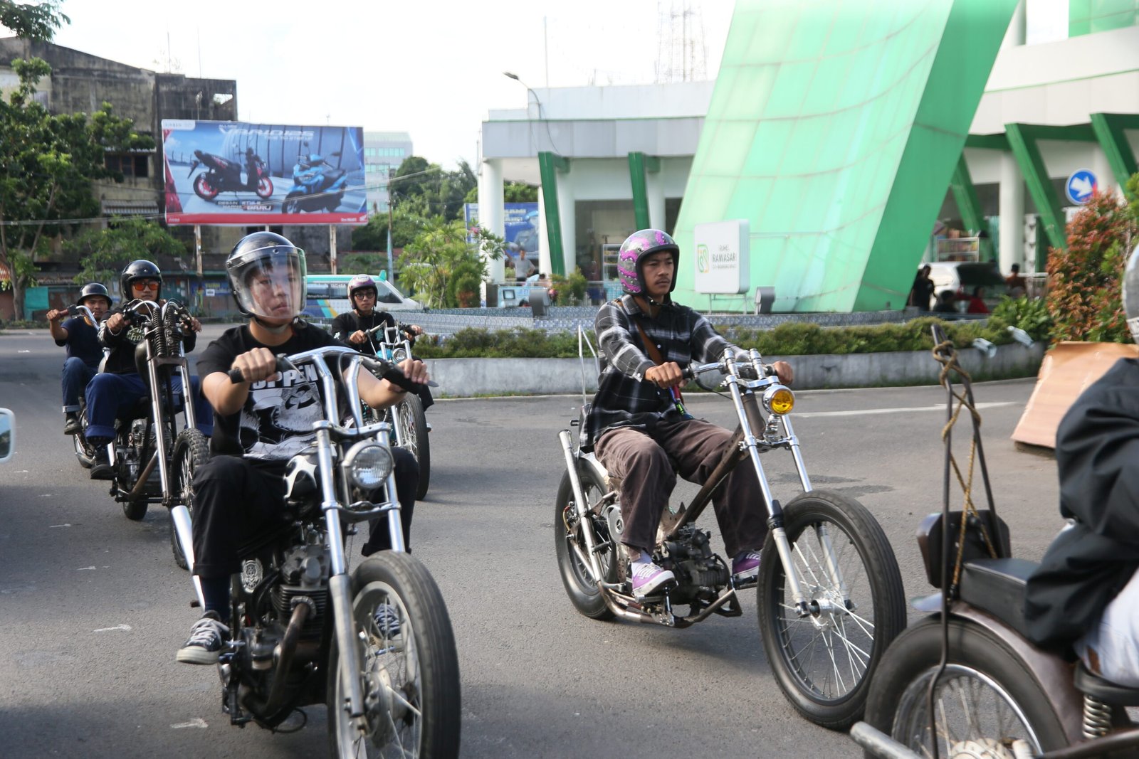 Sekelompok pengendara motor kustom bergaya chopper memasuki kawasan Terminal Rawasari di jalan kota, mengenakan helm dan pakaian kasual, dengan latar bangunan terminal berwarna hijau.