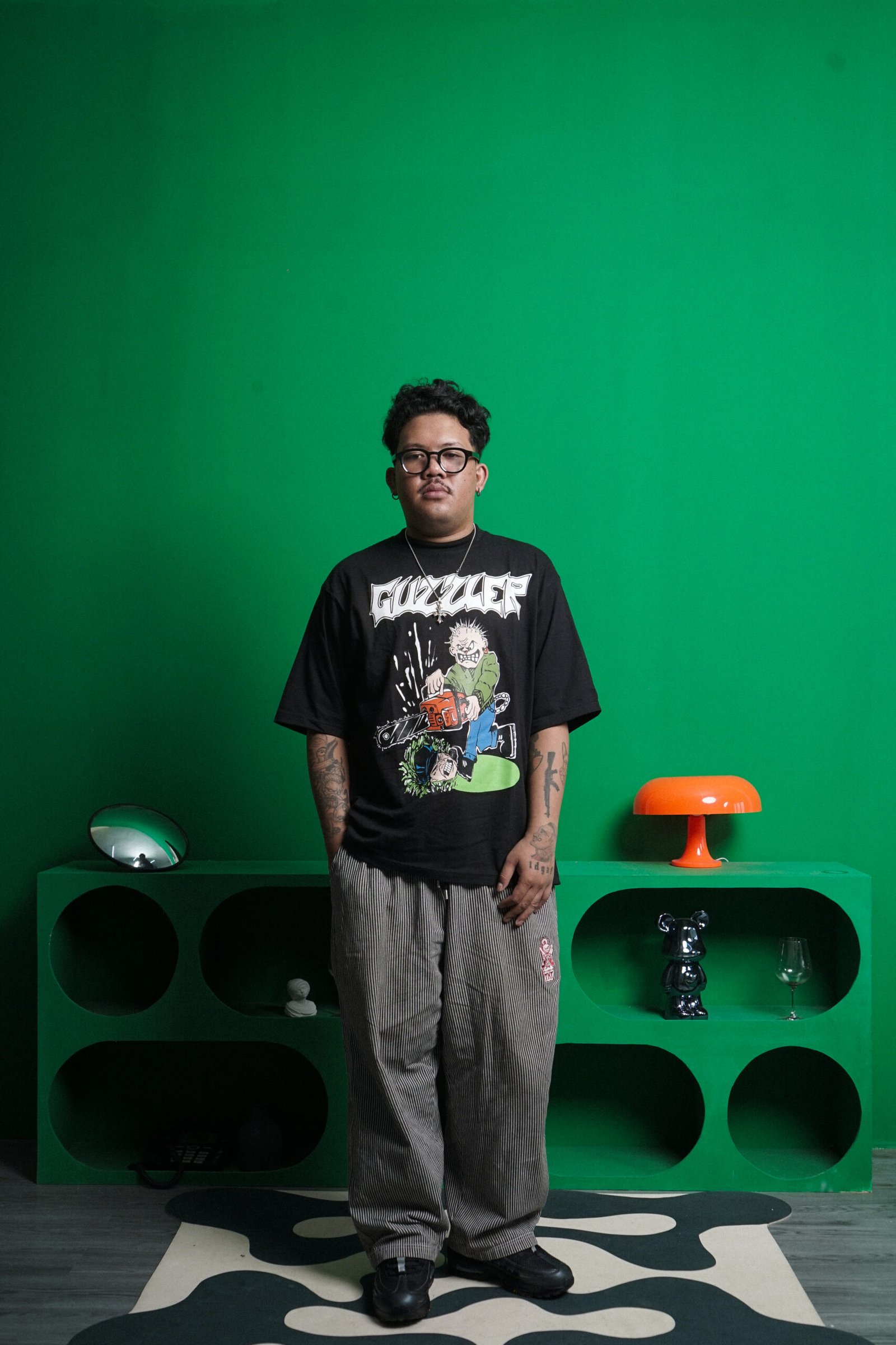Model mengenakan streetwear Guzzler World RETINAL DETACHMENT dengan latar studio hijau