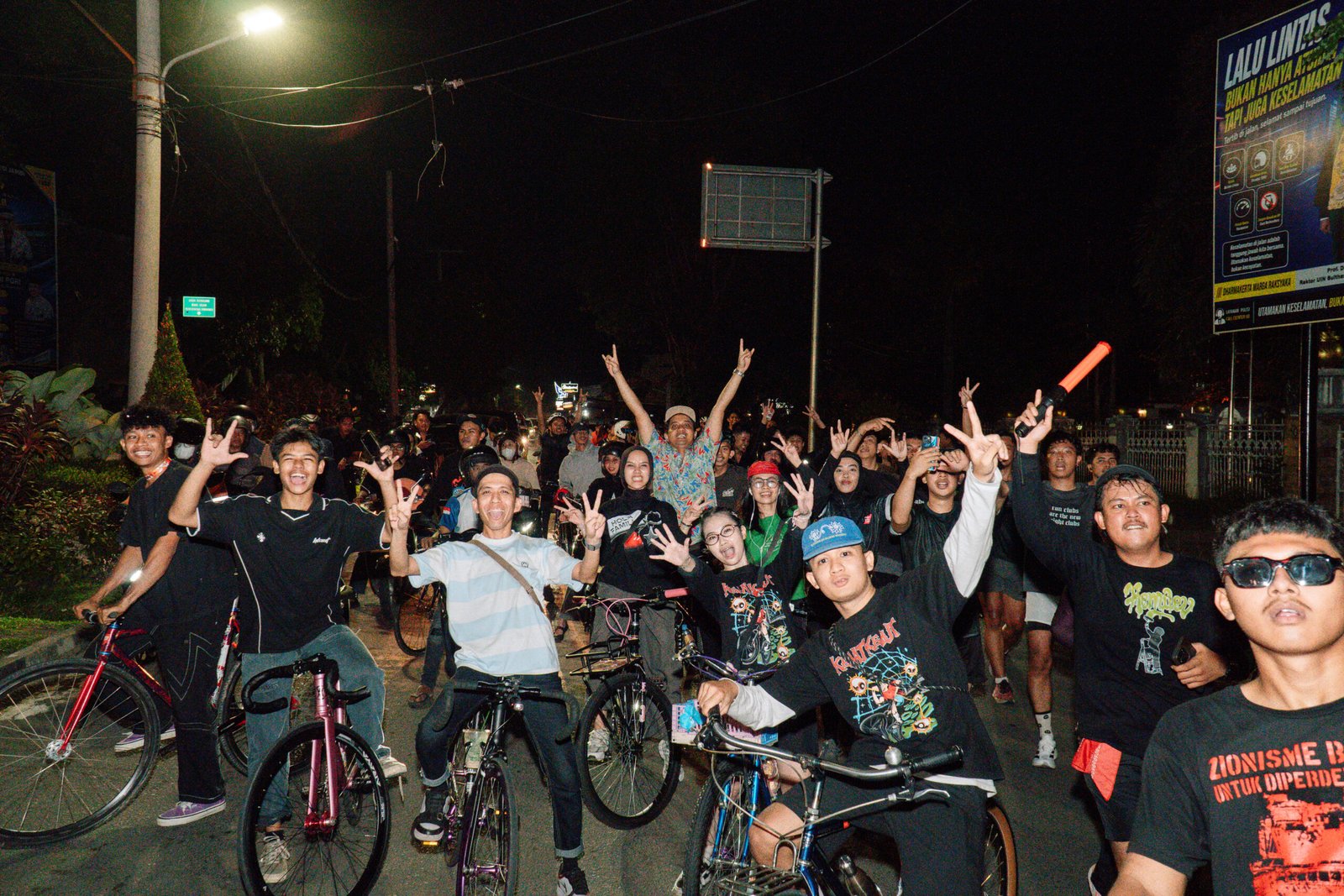 Komunitas Majelis RodaDua Jambi berfoto bersama dalam acara anniversary night ride di jalan kota pada malam hari.