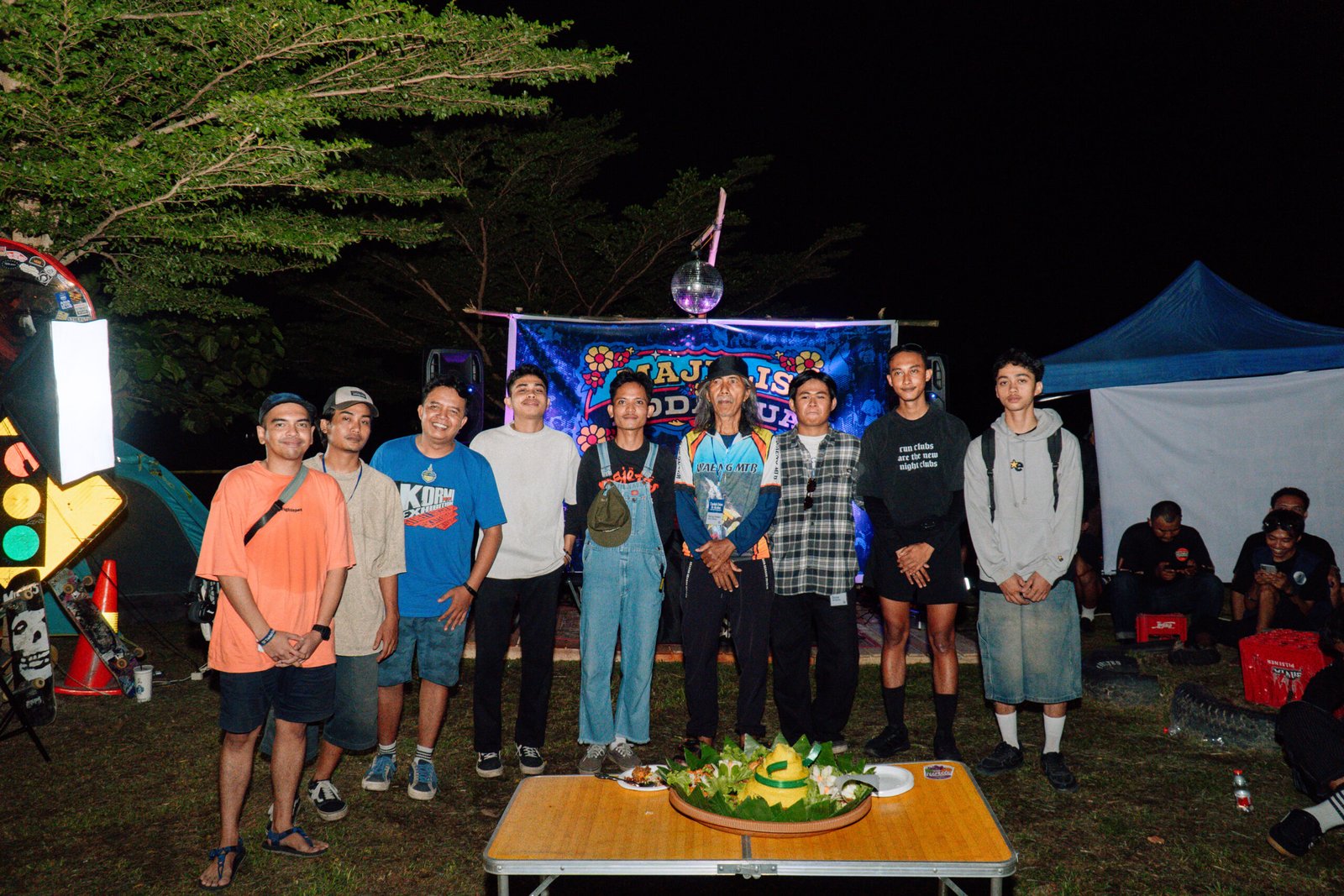 “Foto bersama di acara malam Puncak Annersery hari dengan latar panggung dan suasana outdoor”