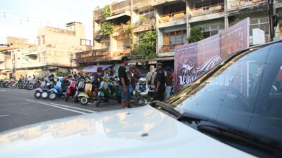 Deretan motor klasik dan skuter terparkir di kawasan Terminal Rawasari, dengan sekelompok orang berbincang di pinggir jalan berlatar bangunan tua.